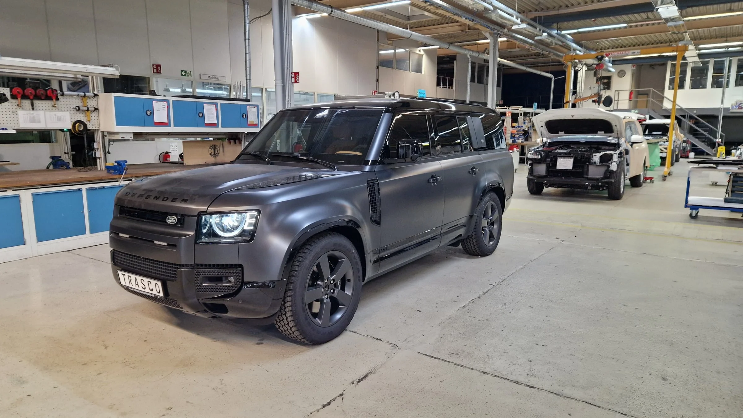 Defender 130 A-KIP® in matter Lackierung in der TRASCO-Fertigungshalle, Dreiviertelansicht von vorn